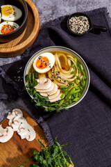 Bowl of asian ramen soup with noodles, spring onion, sliced egg and mushrooms on black table. Japanese dish in black.
- 412248123