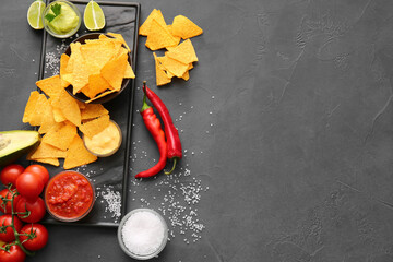Tasty nachos and sauces on dark background