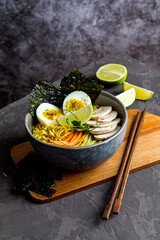 Bowl of asian ramen soup with noodles, spring onion, sliced egg and mushrooms on black table. Japanese dish in black.
- 412248368