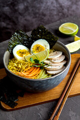 Bowl of asian ramen soup with noodles, spring onion, sliced egg and mushrooms on black table. Japanese dish in black.
- 412248530