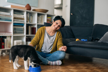 woman playing with her little puppy at home