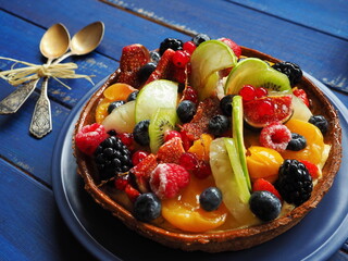 Cake with berries and exotic fruits - raspberry, blueberry, red currant, kiwi, apple, strawberry, orange, mango