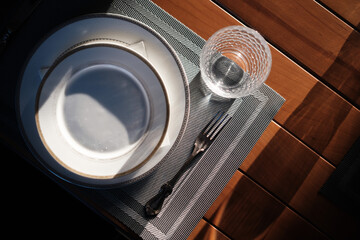 white plate, wineglass, knife and fork on wooden table. Top view.