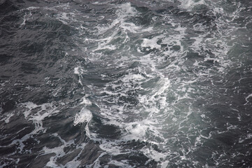 The ocean water with surface foamy sunny day, texture background.