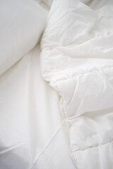 Soft white pillows on messy bed, closeup.