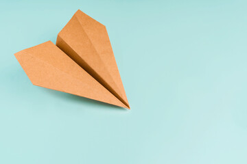 Paper airplane made of craft paper on a light blue background, space for text