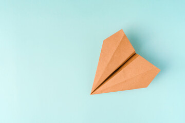 Paper airplane made of craft paper on a light blue background, space for text