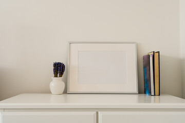 Still life Mock up of silver Picture frame with vase containing flowers and books