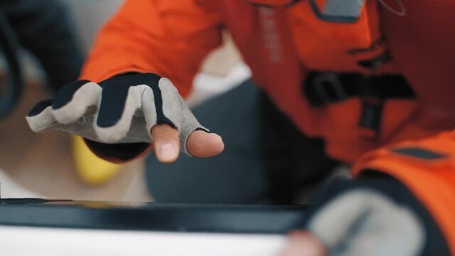 Closeup male hands in gloves use digital display control navigation yacht panel slowmo