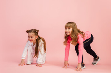Ready to run. Happy kids, girls isolated on coral pink studio background. Look happy, cheerful. Copyspace for ad. Childhood, education, emotions, start up business, facial expression concept.