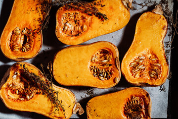 Roasted pumpkins with thyme herbs on baking sheet