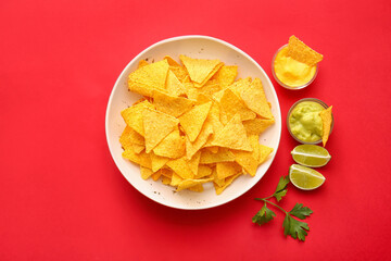 Plate with tasty nachos and sauces on color background