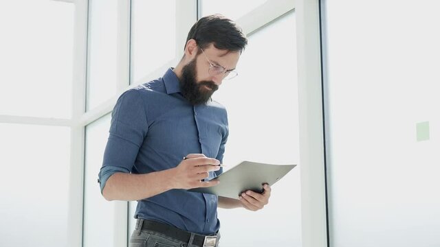 businessman reads a document standing in the office.
