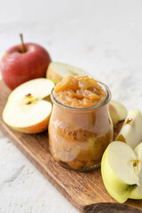 Jar of sweet apple jam on light background