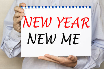 The businessman shows a sheet with the text NEW YEAR NEW ME on a white background. Business concept