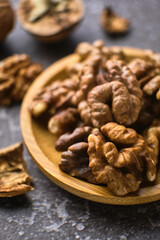 Walnut in wooden bowl on black background with copy space
