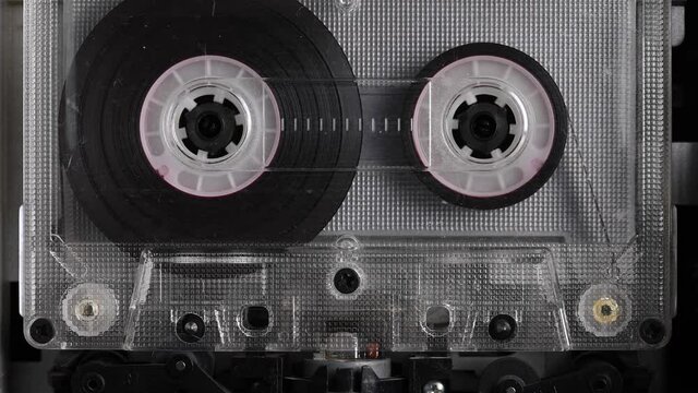 Close-up A tape recorder is playing an audio cassette. Close-up. A vintage audio cassette spins on a blank label tape used to record sound in a retro cassette player. Recording of conversations.