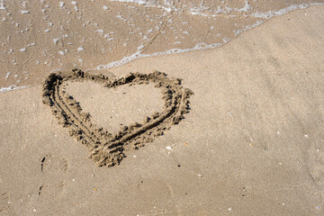 A drawing of a heart on a yellow sand at a beautiful seascape background. Horizontal composition.