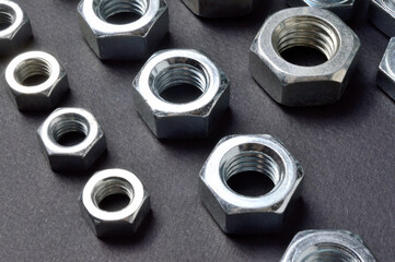 new chrome nuts of different sizes are laid out against a dark background. close-up.