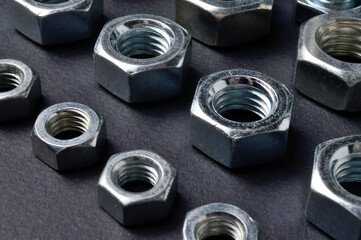 new chrome nuts of different sizes are laid out against a dark background. close-up.