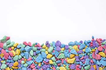 small multi-colored stones, colored soil, sprinkling, decorative stone chips, yellow, pink, blue mosaic pieces on a white background, place for text, mock up for design