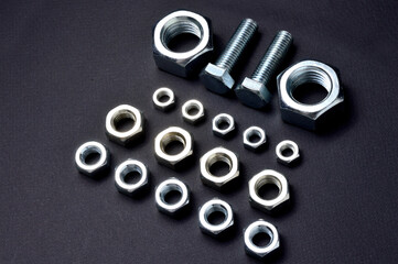 new chrome nuts and bolts of different sizes are laid out against a dark background. close-up.