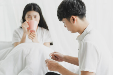 Obraz premium The husband is holding the thermometer to check his wife's temperature in bed