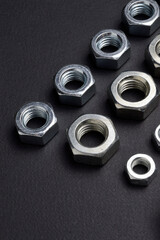 new chrome nuts of different sizes are laid out against a dark background. close-up.