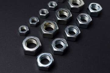 new chrome nuts of different sizes are laid out against a dark background. close-up.