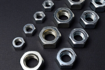 new chrome nuts of different sizes are laid out against a dark background. close-up.