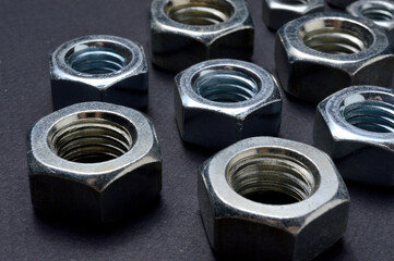 new chrome nuts of different sizes are laid out against a dark background. close-up.