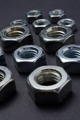 new chrome nuts of different sizes are laid out against a dark background. close-up.