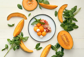 Plate with delicious melon, mozzarella and prosciutto on light background
