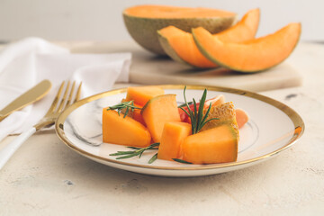 Plate with delicious melon and prosciutto on light background