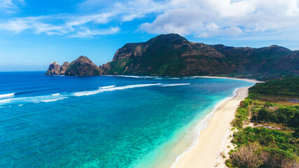Long beatiful beach with white sands and blue sea water. Beautiful aerial view with long waves and a hill in Tropical Beach, West Sumbawa, Indonesia