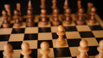 White and black wooden pieces on a chessboard. A chessboard set up during a game on a black background