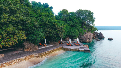 Drone view of beach chairs and umberella on tropical ocean beach in Moyo Island, Sumbawa, Indonesia