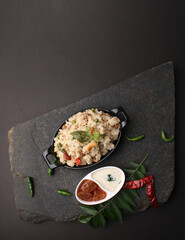 Rice upma, a south Indian vegetarian breakfast made from shredded rice and vegetables like carrot andpeas, with coconut chutney as a side dish.