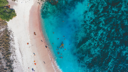 People swimming and playing on the beach. Tourists on the Pink Beach, Komodo National Park, Labuan Bajo, Indonesia. A bird eye view photo captured with drone.