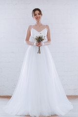 Beautiful happy sophisticated bride in a wedding dress in a light room