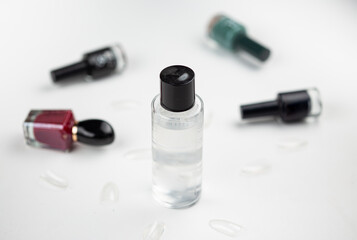 a bottle of nails polish remover with fake nails and polish bottles in the background