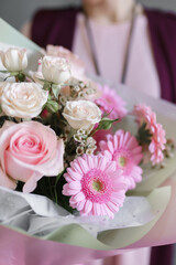 image of a girl in apron holding a flower in her hands with a manicure on a grey background	