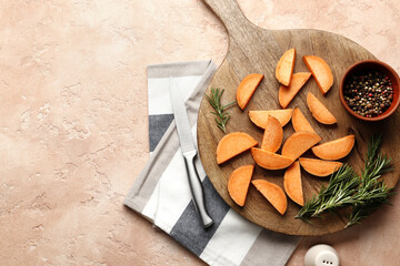 Composition of fresh sweet sliced potatoes, rosemary spice, pepper, salt, knife, sliced kitchen towel on a wooden background close-up.