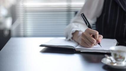 Close-up image of a businesswoman taking notes on the desk.