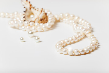 Close-up of natural pearl necklace with clam shell and scattered beads.