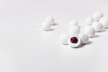 Sweet balls of cranberries in powdered sugar scattered on a white background.