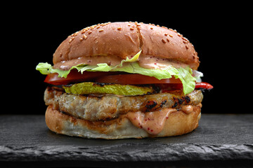 Burger, cheeseburger, hamburger with meat cutlet, zucchiniю  cheese, lettuce and tomato, on a black background