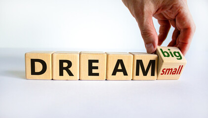 Dream small or big symbol. Businessman turns wooden cubes and changes words 'dream small' to 'dream big'. Beautiful white background, copy space. Business and dream small or big concept.