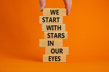 Symbol of building success foundation. Businessman put wooden blocks on the stack of wooden blocks. Words 'we start with stars in our eyes'. Beautiful orange background, copy space. Business concept.