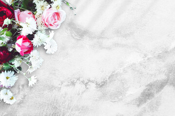 Fototapeta na wymiar Bouquet of flowers on a concrete table. Red and pink roses, white daisies. Old white and gray background. Floral mockup for Birthday, Valentine`s day, Women`s day. Top view, flat lay, copy space